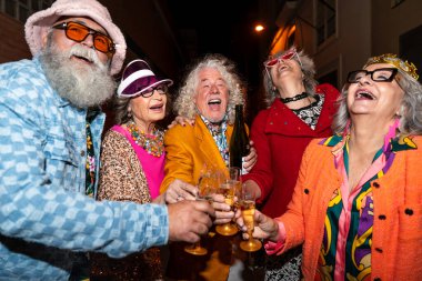 Süslü elbiseli mutlu son sınıf arkadaşları gecenin bir yarısı şehir sokaklarında parti veriyor. Şık kıyafetler giyen ve dışarıda eğlenen neşeli yaşlı insanlar.