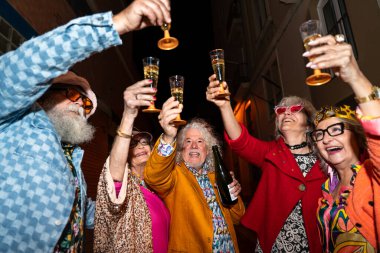 Süslü elbiseli mutlu son sınıf arkadaşları gecenin bir yarısı şehir sokaklarında parti veriyor. Şık kıyafetler giyen ve dışarıda eğlenen neşeli yaşlı insanlar.