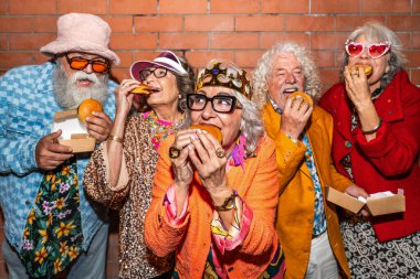 Süslü elbiseli mutlu son sınıf arkadaşları gecenin bir yarısı şehir sokaklarında parti veriyor. Şık kıyafetler giyen ve dışarıda eğlenen neşeli yaşlı insanlar.