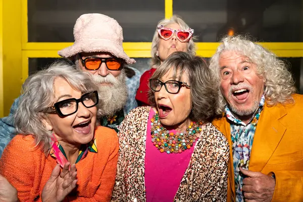 Süslü elbiseli mutlu son sınıf arkadaşları gecenin bir yarısı şehir sokaklarında parti veriyor. Şık kıyafetler giyen ve dışarıda eğlenen neşeli yaşlı insanlar.