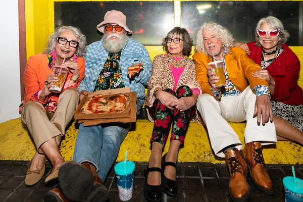 Süslü elbiseli mutlu son sınıf arkadaşları gecenin bir yarısı şehir sokaklarında parti veriyor. Şık kıyafetler giyen ve dışarıda eğlenen neşeli yaşlı insanlar.