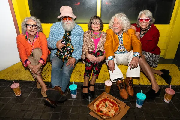 Süslü elbiseli mutlu son sınıf arkadaşları gecenin bir yarısı şehir sokaklarında parti veriyor. Şık kıyafetler giyen ve dışarıda eğlenen neşeli yaşlı insanlar.