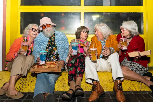 Süslü elbiseli mutlu son sınıf arkadaşları gecenin bir yarısı şehir sokaklarında parti veriyor. Şık kıyafetler giyen ve dışarıda eğlenen neşeli yaşlı insanlar.