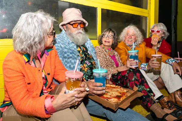 Süslü elbiseli mutlu son sınıf arkadaşları gecenin bir yarısı şehir sokaklarında parti veriyor. Şık kıyafetler giyen ve dışarıda eğlenen neşeli yaşlı insanlar.