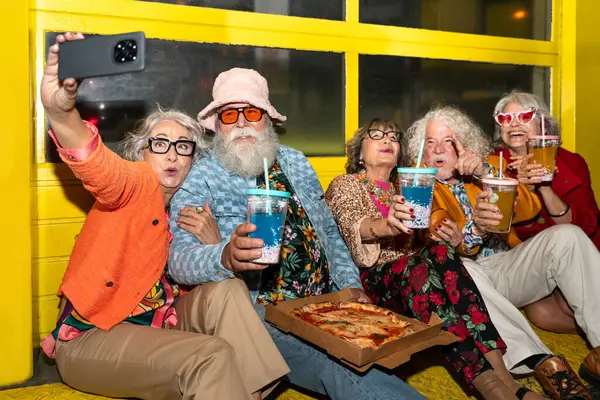 Süslü elbiseli mutlu son sınıf arkadaşları gecenin bir yarısı şehir sokaklarında parti veriyor. Şık kıyafetler giyen ve dışarıda eğlenen neşeli yaşlı insanlar.