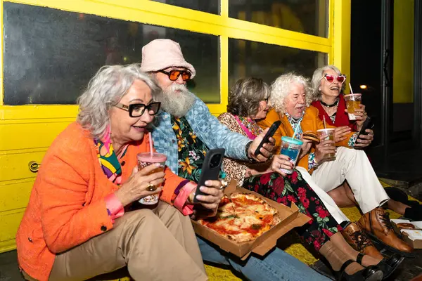 Süslü elbiseli mutlu son sınıf arkadaşları gecenin bir yarısı şehir sokaklarında parti veriyor. Şık kıyafetler giyen ve dışarıda eğlenen neşeli yaşlı insanlar.