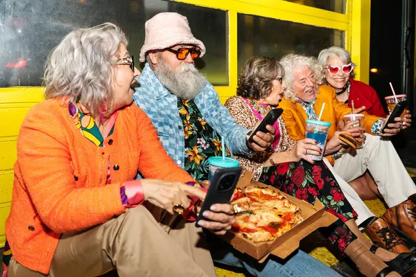 Süslü elbiseli mutlu son sınıf arkadaşları gecenin bir yarısı şehir sokaklarında parti veriyor. Şık kıyafetler giyen ve dışarıda eğlenen neşeli yaşlı insanlar.