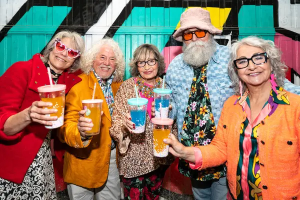 Süslü elbiseli mutlu son sınıf arkadaşları gecenin bir yarısı şehir sokaklarında parti veriyor. Şık kıyafetler giyen ve dışarıda eğlenen neşeli yaşlı insanlar.