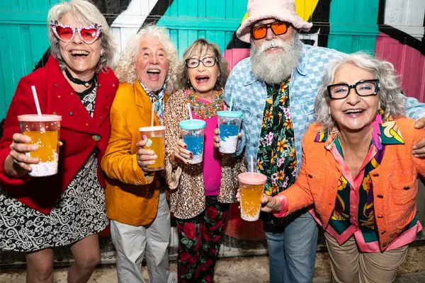 Süslü elbiseli mutlu son sınıf arkadaşları gecenin bir yarısı şehir sokaklarında parti veriyor. Şık kıyafetler giyen ve dışarıda eğlenen neşeli yaşlı insanlar.