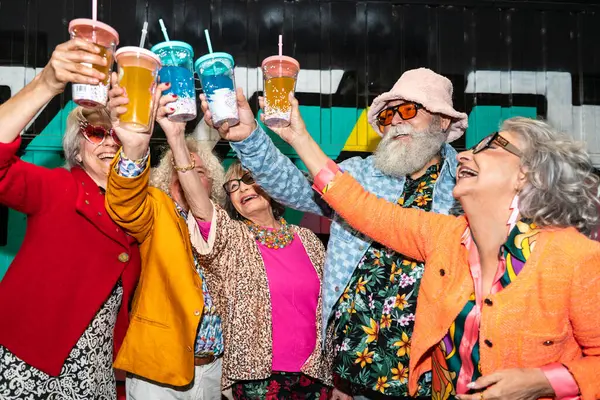 Süslü elbiseli mutlu son sınıf arkadaşları gecenin bir yarısı şehir sokaklarında parti veriyor. Şık kıyafetler giyen ve dışarıda eğlenen neşeli yaşlı insanlar.