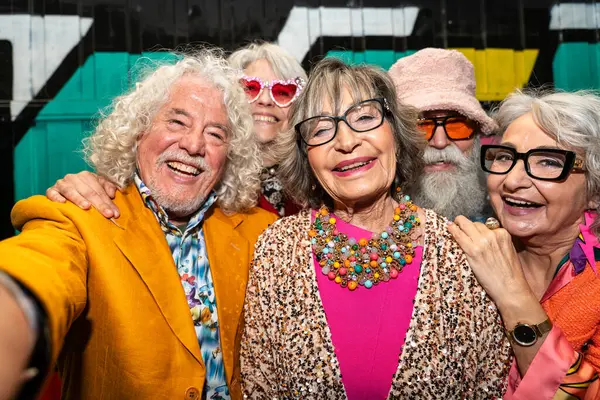 Süslü elbiseli mutlu son sınıf arkadaşları gecenin bir yarısı şehir sokaklarında parti veriyor. Şık kıyafetler giyen ve dışarıda eğlenen neşeli yaşlı insanlar.