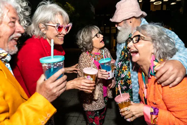Süslü elbiseli mutlu son sınıf arkadaşları gecenin bir yarısı şehir sokaklarında parti veriyor. Şık kıyafetler giyen ve dışarıda eğlenen neşeli yaşlı insanlar.
