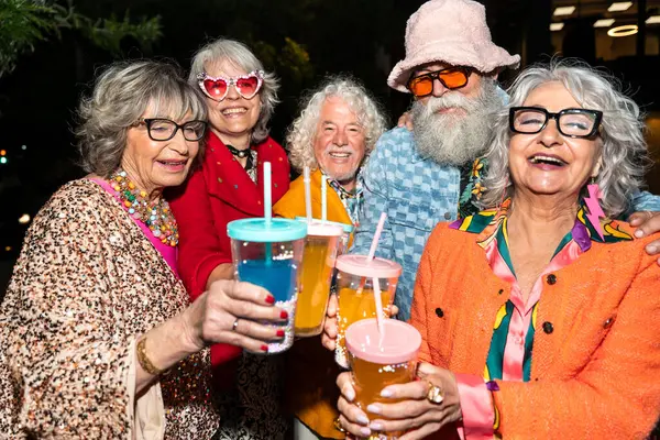 Süslü elbiseli mutlu son sınıf arkadaşları gecenin bir yarısı şehir sokaklarında parti veriyor. Şık kıyafetler giyen ve dışarıda eğlenen neşeli yaşlı insanlar.