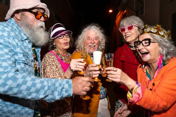 Süslü elbiseli mutlu son sınıf arkadaşları gecenin bir yarısı şehir sokaklarında parti veriyor. Şık kıyafetler giyen ve dışarıda eğlenen neşeli yaşlı insanlar.