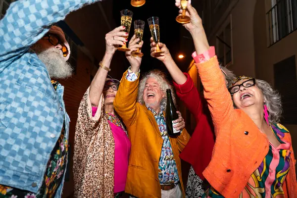 Süslü elbiseli mutlu son sınıf arkadaşları gecenin bir yarısı şehir sokaklarında parti veriyor. Şık kıyafetler giyen ve dışarıda eğlenen neşeli yaşlı insanlar.