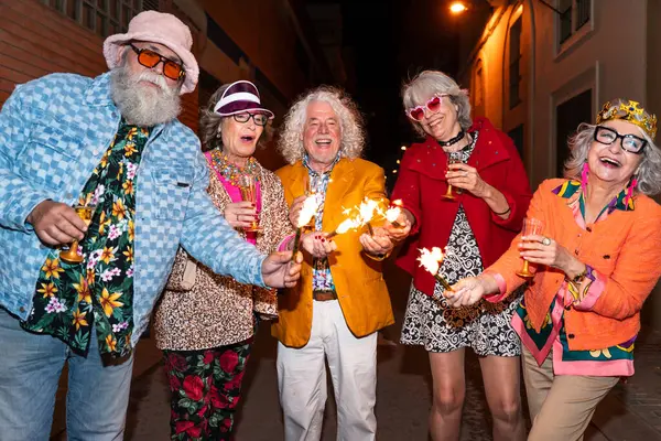 Süslü elbiseli mutlu son sınıf arkadaşları gecenin bir yarısı şehir sokaklarında parti veriyor. Şık kıyafetler giyen ve dışarıda eğlenen neşeli yaşlı insanlar.