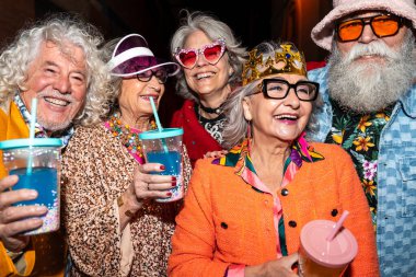 Süslü elbiseli mutlu son sınıf arkadaşları gecenin bir yarısı şehir sokaklarında parti veriyor. Şık kıyafetler giyen ve dışarıda eğlenen neşeli yaşlı insanlar.