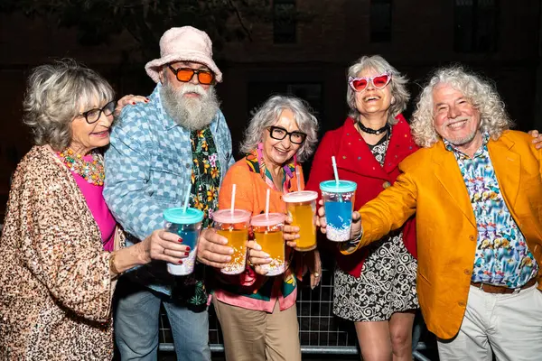 Süslü elbiseli mutlu son sınıf arkadaşları gecenin bir yarısı şehir sokaklarında parti veriyor. Şık kıyafetler giyen ve dışarıda eğlenen neşeli yaşlı insanlar.