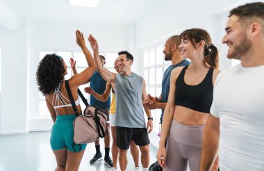 Çok ırklı spor yapan bir grup sporcu, başarılı bir eğitim programının ardından başarıları beşlik çakarak ve el sıkışarak antreman yapan bir grup sporcu.