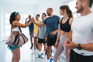 Spor salonunda egzersiz yapan çok ırklı bir grup sporcu başarılarını beşlikle kutlayan gülümseyen sporcular işlevsel bir antrenmanı tamamladıktan sonra 