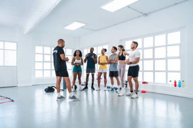 Spor salonunda spor yapan çok ırklı bir grup sporcu, spor salonundaki sporculara işlevsel egzersiz stratejilerini anlatıyor ve performans geliştirme egzersizlerini tartışıyorlar.