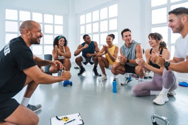 Çok ırklı spor yapan bir grup sporcu çeşitli sporculardan oluşan bir beden eğitimi grubunda başarılı bir eğitim sonrasında kişisel antrenörlerini alkışlıyor ve kutluyorlar.