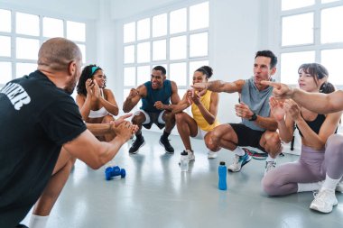 Çok ırklı spor yapan bir grup sporcu, bir egzersiz sırasında birbirlerini motive eden ve tezahürat yapan beden eğitimi sınıfındaki sporculardan oluşan bir grup.