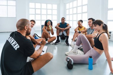 Çok ırklı spor yapan bir grup sporcu, işlevsel eğitim sırasında çeşitli sporcularla yapılan bir tartışma sırasında antrenman sınıfında antrenman yapıyor.