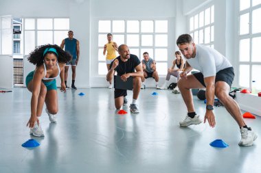 Çok ırklı spor yapan bir grup sporcu, beden eğitimi sınıfında çok ırklı sporculardan oluşan bir grupta spor salonunda külahlarla çeviklik tatbikatları yapıyorlar.