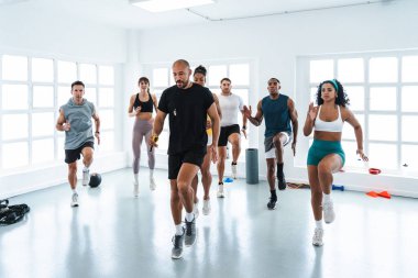 Çok ırklı spor yapan bir grup sporcu, yüksek yoğunluklu idman sırasında çeşitli sporculara rehberlik ediyor.