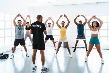 Çok ırklı bir grup sporcu beden eğitimi sınıfında çeşitli sporcular eşzamanlı atlama hareketleri yapıyor. İşlevsel antrenman sırasında antrenör rehberliğinde. 