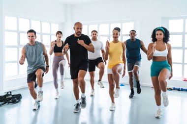 Çok ırklı spor yapan bir grup sporcu, parlak bir spor salonunda, işlevsel bir antrenman sırasında, beden eğitimi sınıfında çok ırklı sporcular koşuyor.