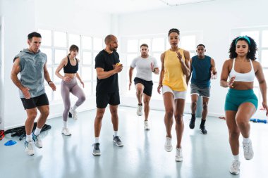 Yüksek yoğunluklu işlevsel eğitim sırasında spor sınıfında koşan çeşitli sporculardan oluşan çok ırklı bir grup.