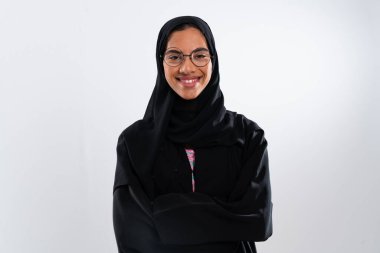 Orta Doğu 'da Müslüman kültürünü, modasını ve kadın gücünü temsil eden geleneksel siyah abaya ve tesettüre sahip genç, gülümseyen bir Arap kadının stüdyo portresi.