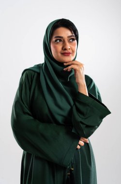 Stüdyo portresi zarif, geleneksel giyinmiş, zarif, yeşil elbiseli bir Arap kadının derin bir tefekkür ve düşüncelere dalmışken nazikçe çenesine dokunmasını içeriyor.