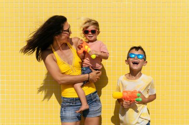 Mutlu güzel Asyalı aile yaz tatilinde kumsalda eğleniyor. Çinli anne ve melez Asyalı çocuklar denizde vakit geçiriyorlar. Aile, annelik ve çeşitlilik kavramları.