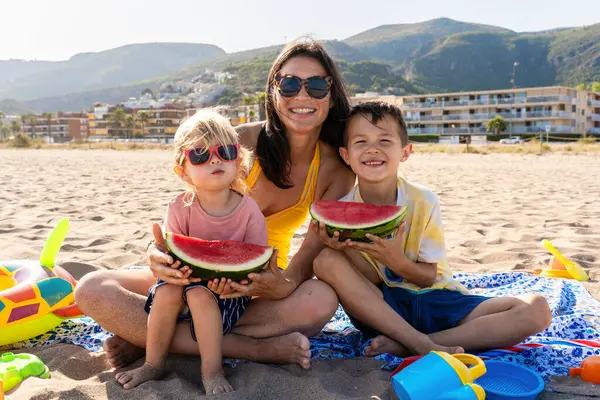 Mutlu güzel Asyalı aile yaz tatilinde kumsalda eğleniyor. Çinli anne ve melez Asyalı çocuklar denizde vakit geçiriyorlar. Aile, annelik ve çeşitlilik kavramları.