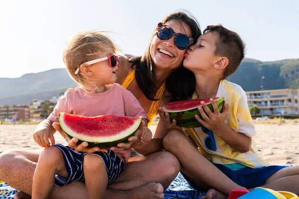 Mutlu güzel Asyalı aile yaz tatilinde kumsalda eğleniyor. Çinli anne ve melez Asyalı çocuklar denizde vakit geçiriyorlar. Aile, annelik ve çeşitlilik kavramları.