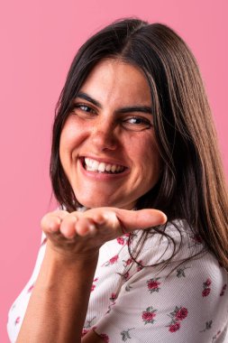 Neşeli bir yüzü olan genç bir kadının portresi pembe bir arka plana öpücük yolluyor. Onun eşsiz stili ve enerjik enerjisi büyüleyici ve neşeli bir atmosfer yaratır.