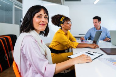 Modern ofisteki toplantı sırasında proje üzerinde işbirliği yapan iş ekibi, dizüstü bilgisayar kullanıyor ve not alıyor, profesyonel ortamda takım çalışması ve üretkenlik sergiliyor