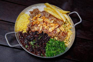 Siyah arka planda et, pirinç ve sebzeyle kızartılmış tava.