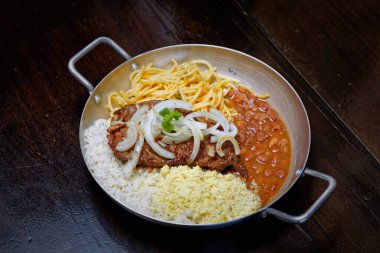 Brezilya bifteği, soğan, fasulye, pirinç ve farofa.