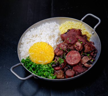 Sosis, lahana, pirinç ve portakallı Brezilya feijoadası.