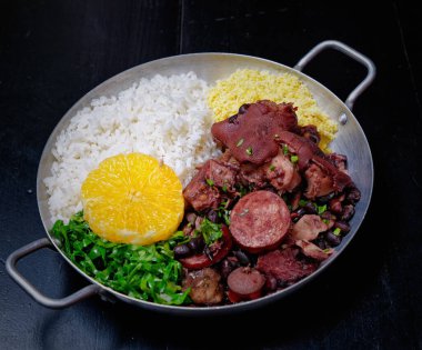 Sosis, lahana, pirinç ve portakallı Brezilya feijoadası.