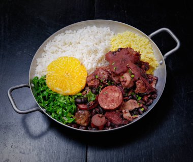 Sosis, lahana, pirinç ve portakallı Brezilya feijoadası.