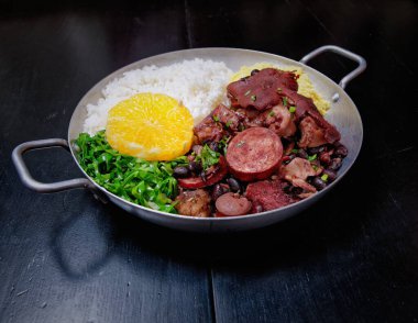 Sosis, lahana, pirinç ve portakallı Brezilya feijoadası.