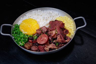 Sosis, lahana, pirinç ve portakallı Brezilya feijoadası.