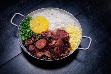 Sosis, lahana, pirinç ve portakallı Brezilya feijoadası.