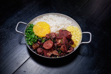 Sosis, lahana, pirinç ve portakallı Brezilya feijoadası.