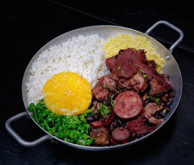 Sosis, lahana, pirinç ve portakallı Brezilya feijoadası.